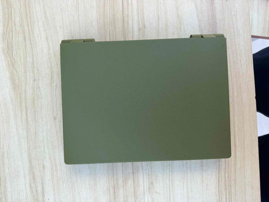An olive green rectangular hard case or box with rounded corners, photographed from above on a light wood-grain surface.