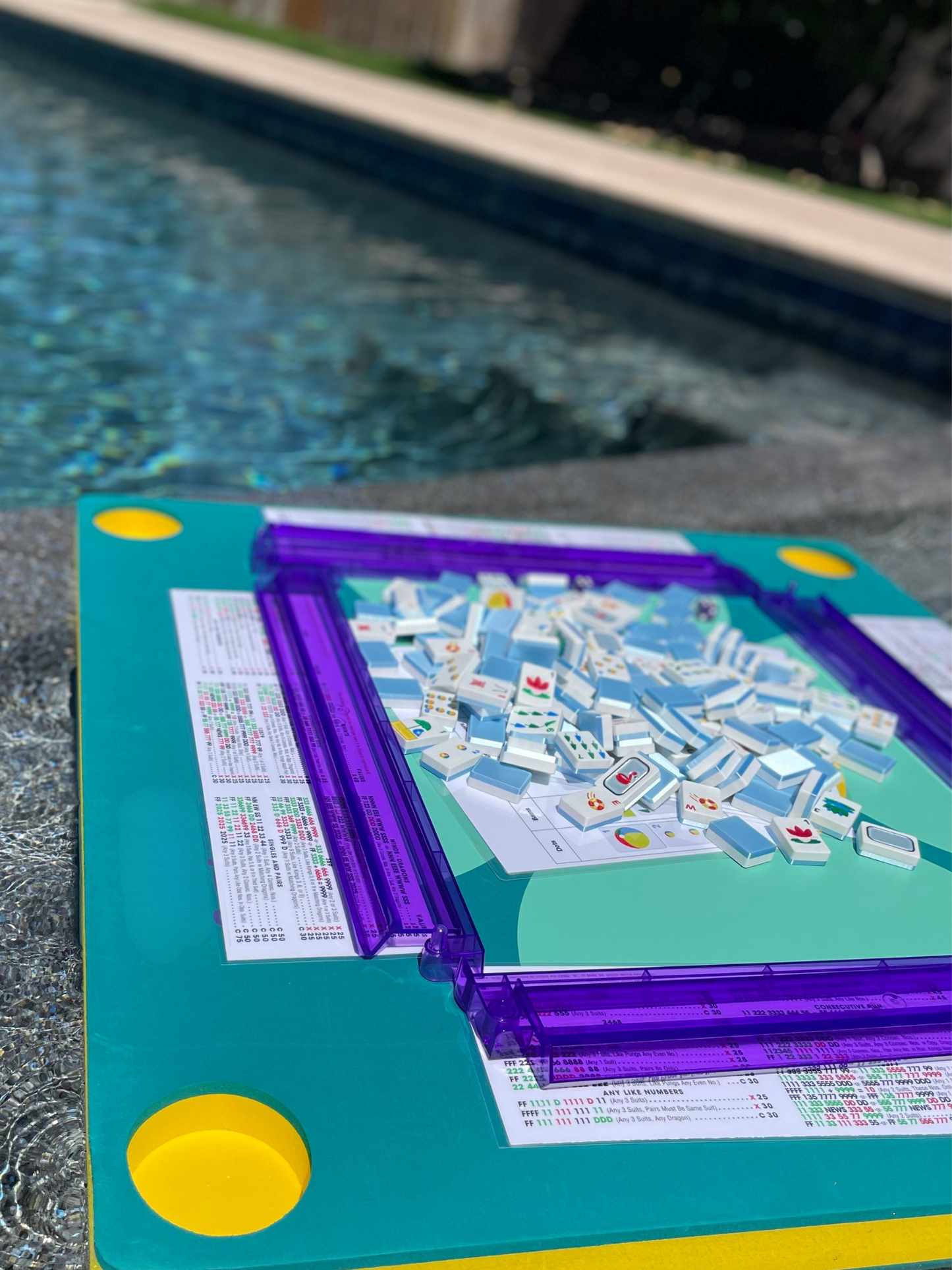 Floating Mahjong tiles on a waterproof pool table with colorful racks, designed for poolside play.