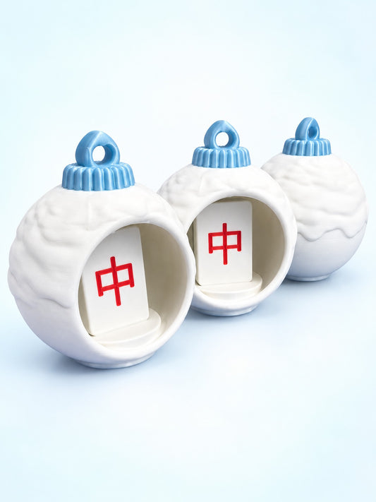 Side view of three mahjong bauble ornaments by Spools, two showing red dragon tiles inside