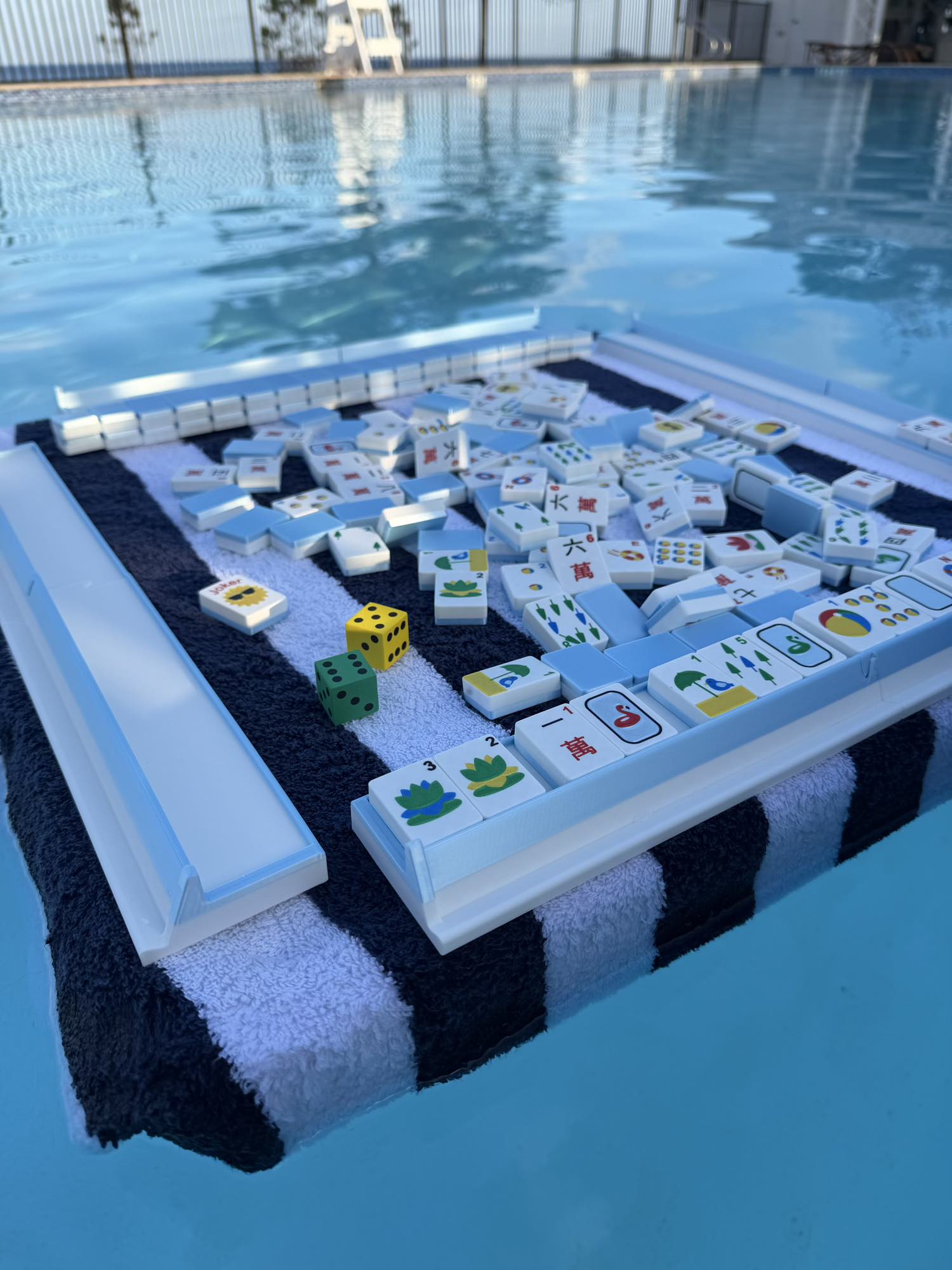 A picture of pink mahjong tiles with a nautical theme floating in a pool