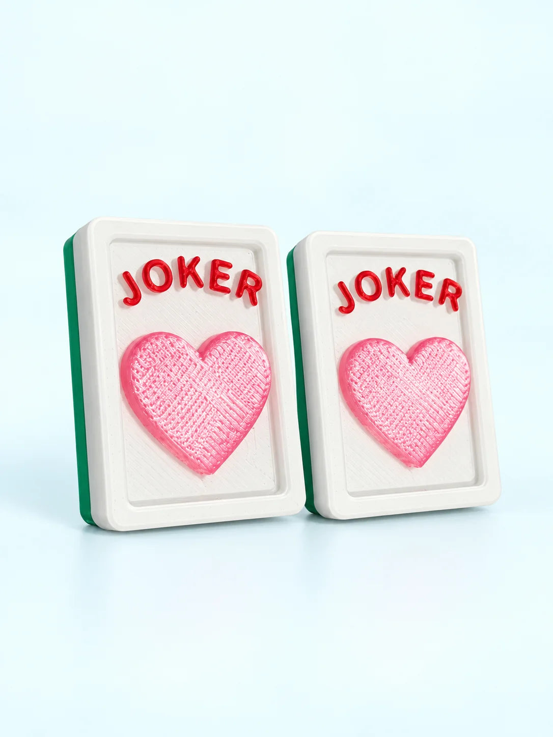Two heart joker mahjong tiles with a pink heart under red JOKER lettering, by Spools