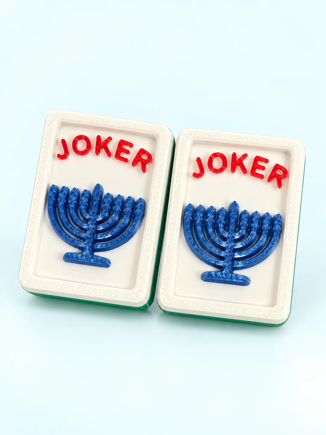 Front view of two menorah joker mahjong tiles with a blue menorah and green backs, by Spools