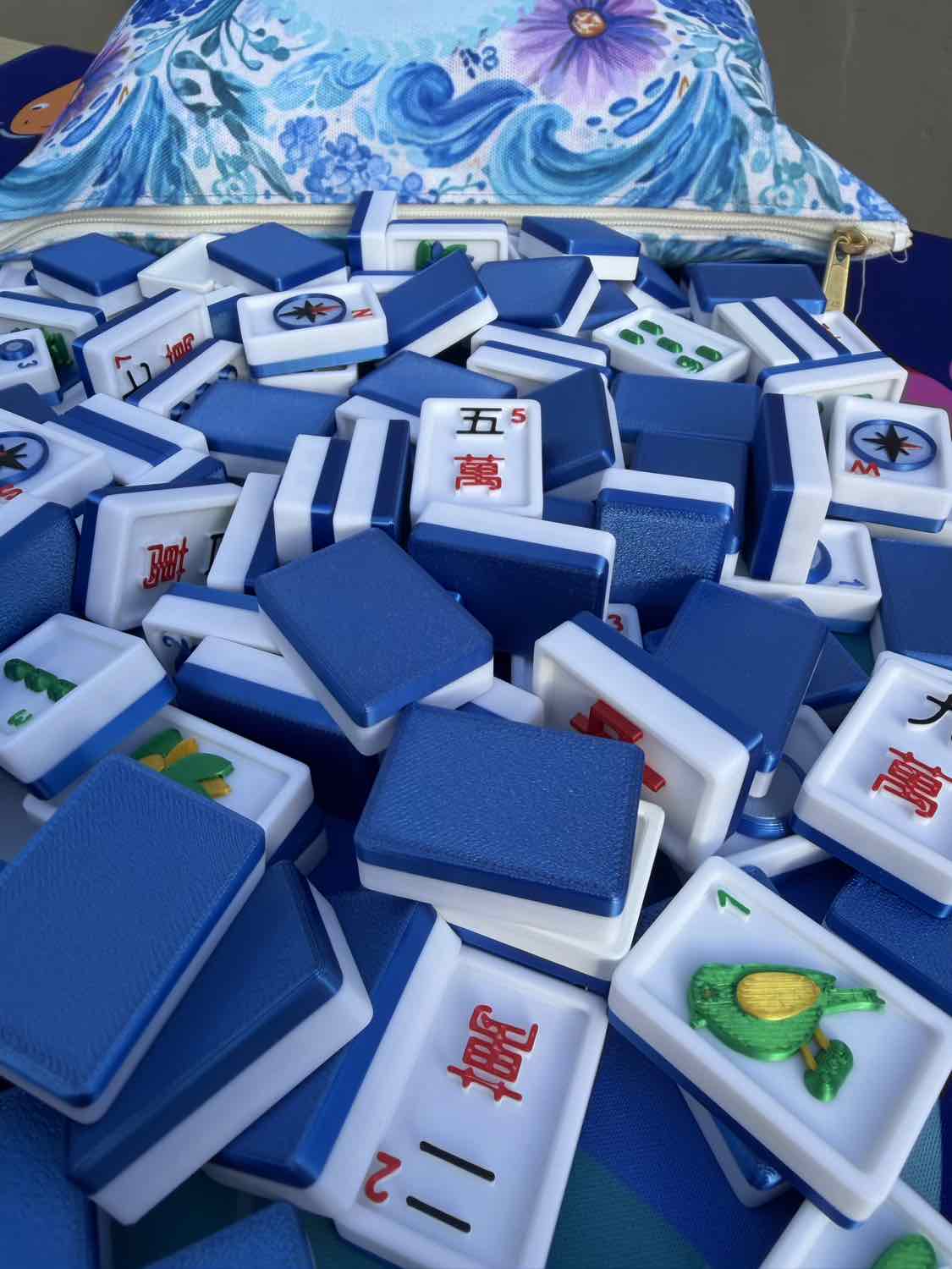 Stack of blue and white Mahjong tiles with a colorful bag in the background
