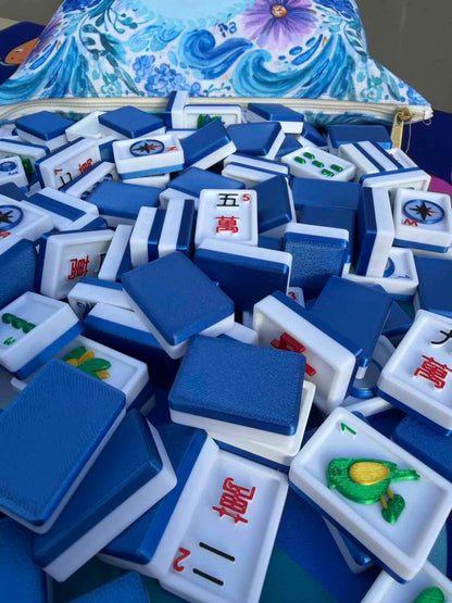 Stack of blue and white Mahjong tiles with a colorful bag in the background