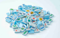 A pile of miniature light blue and white Mahjong tiles with colorful Chinese characters and symbols, scattered on a clean white background.