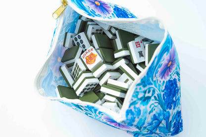 A blue and white floral zippered pouch filled with mahjong tiles, photographed from above on a white background.