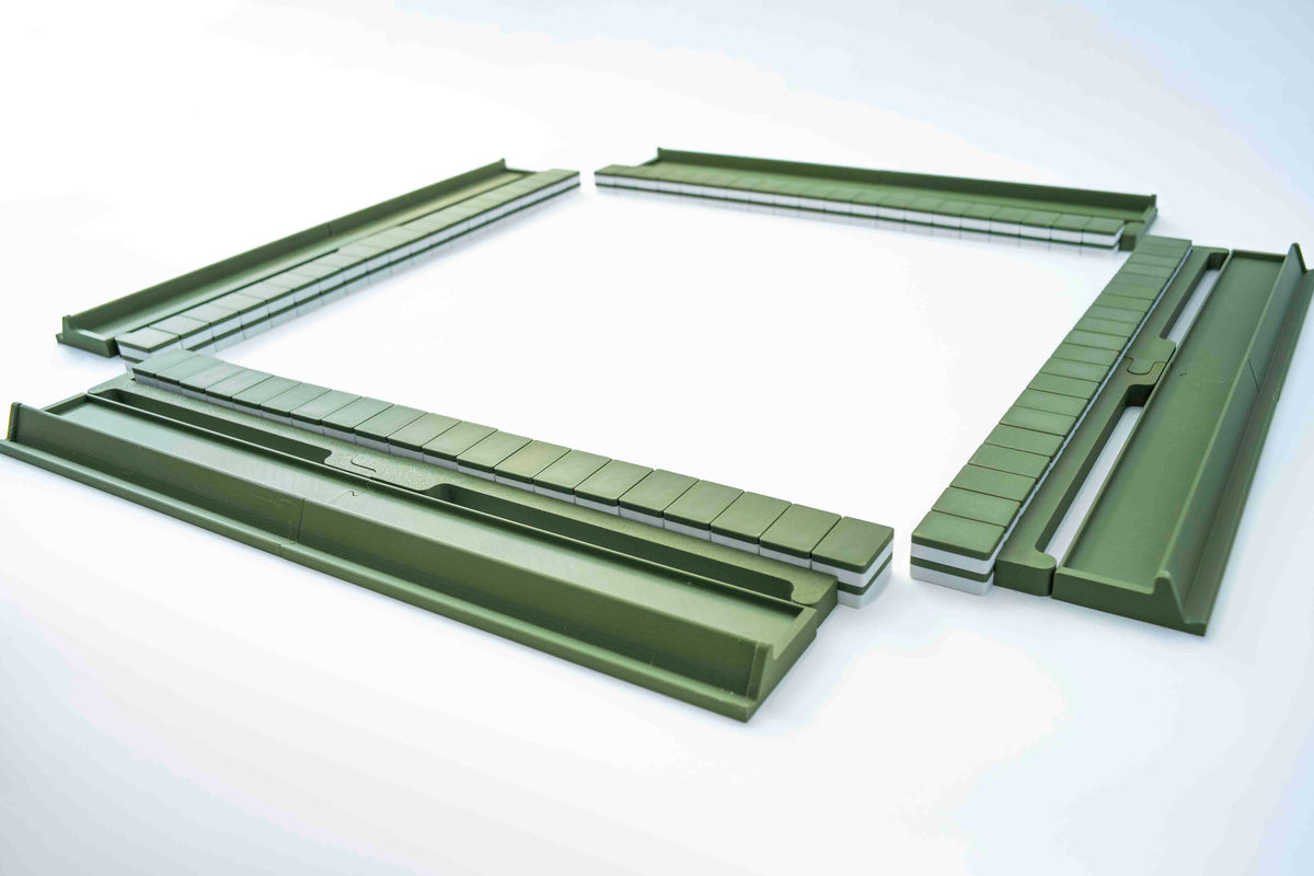 A set of olive green plastic mahjong racks or channel components arranged in a loose square on a clean white background.