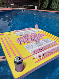 Foam pool table with pink and yellow design in a pool with floating mahjong tiles