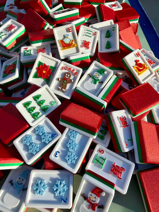 A pile of Mahjong tiles with festive Christmas designs, including holiday numbers, snowflakes, a gingerbread man, a Santa Claus tile, and red, green, and white backs.