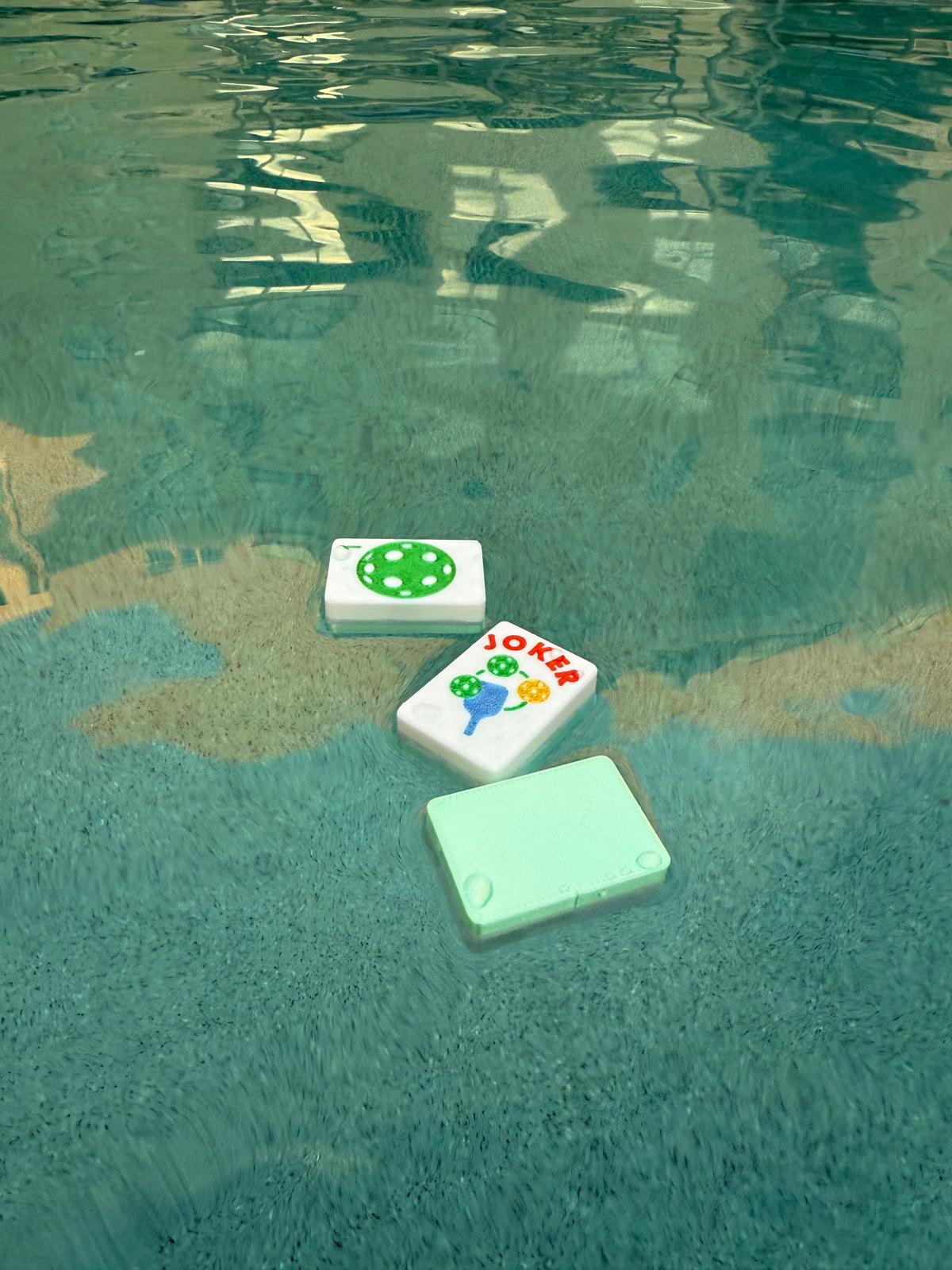 Pickleball Mahjong tiles floating in a pool demonstrating waterproof and pool-friendly design