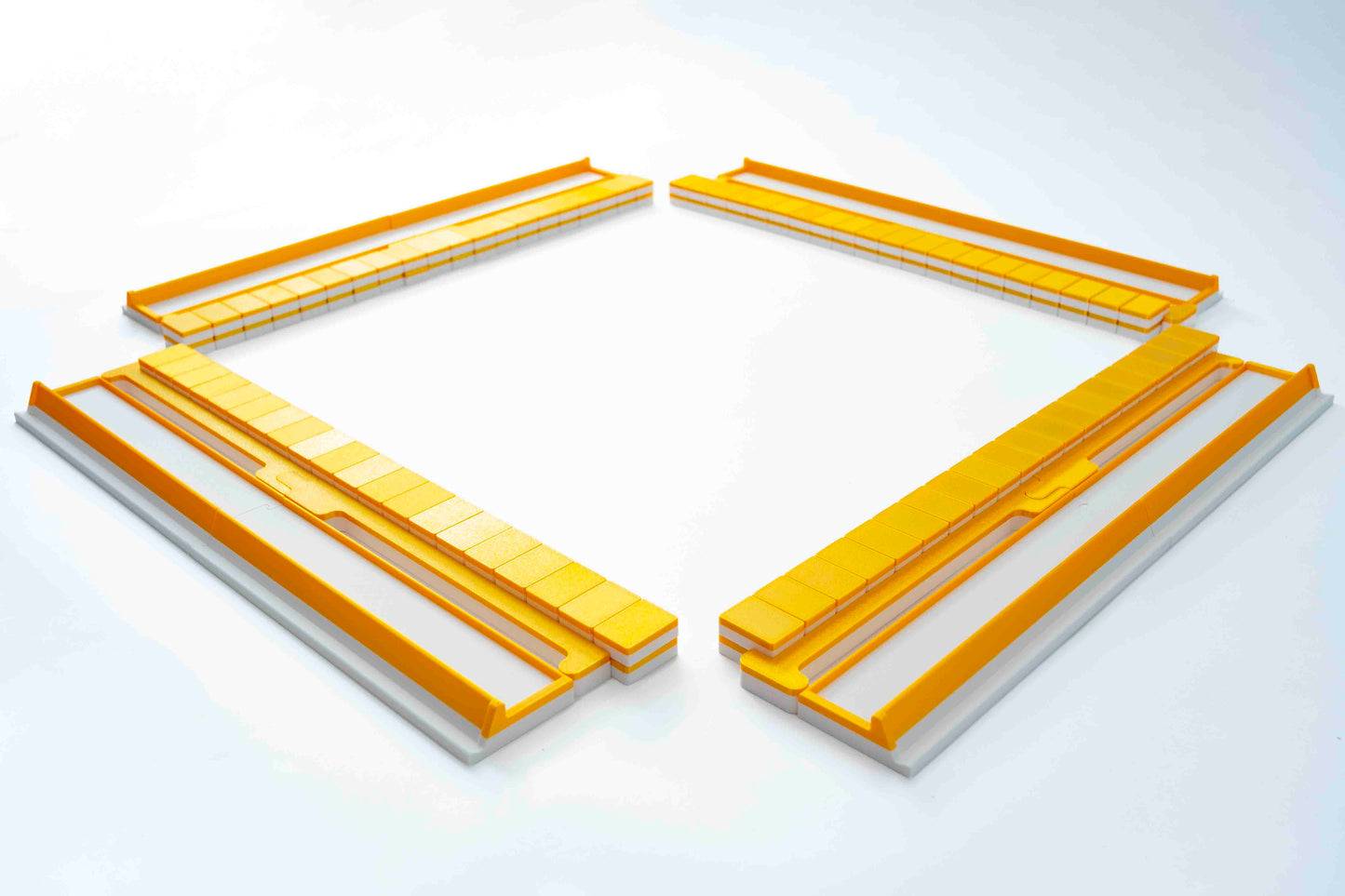 Four long rectangular Gold Mahjong tiles, racks, and pushers arranged in a square-like layout on a clean white background.