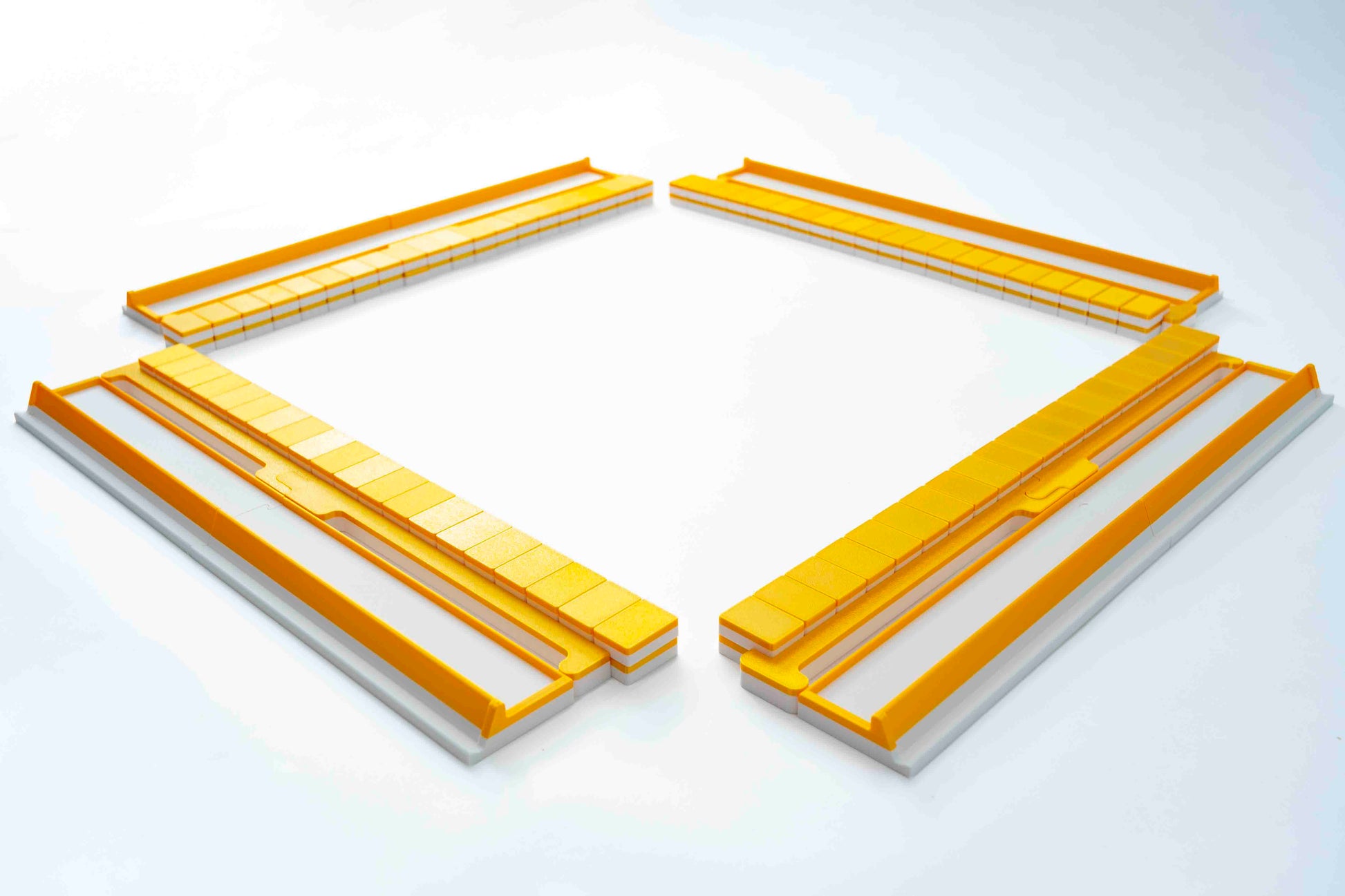 Four long rectangular Gold Mahjong tiles, racks, and pushers arranged in a square-like layout on a clean white background.