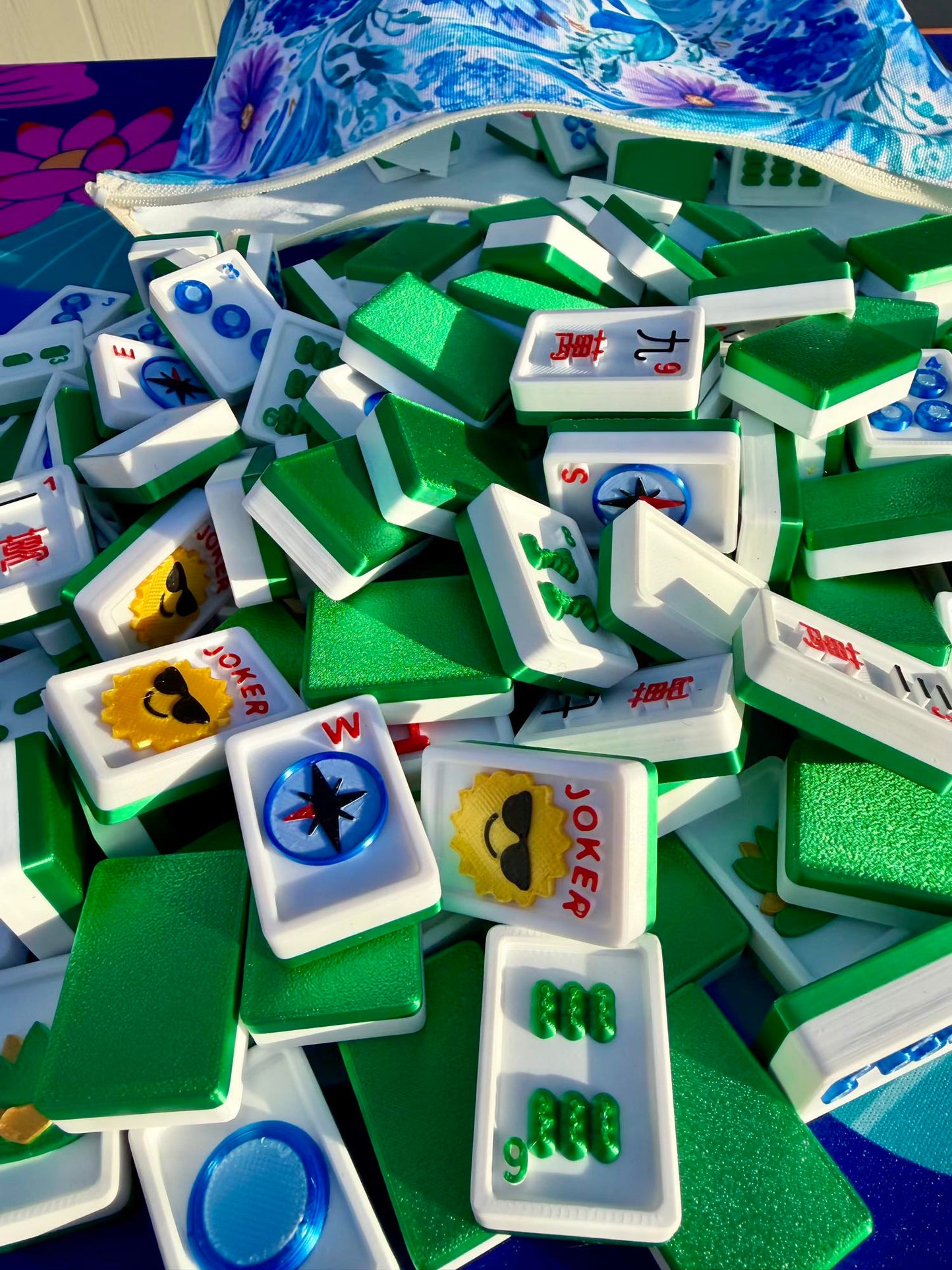 Green Travel Mahjong Tiles - 3D spill from an open floral-blue pouch, tiles piled close together.