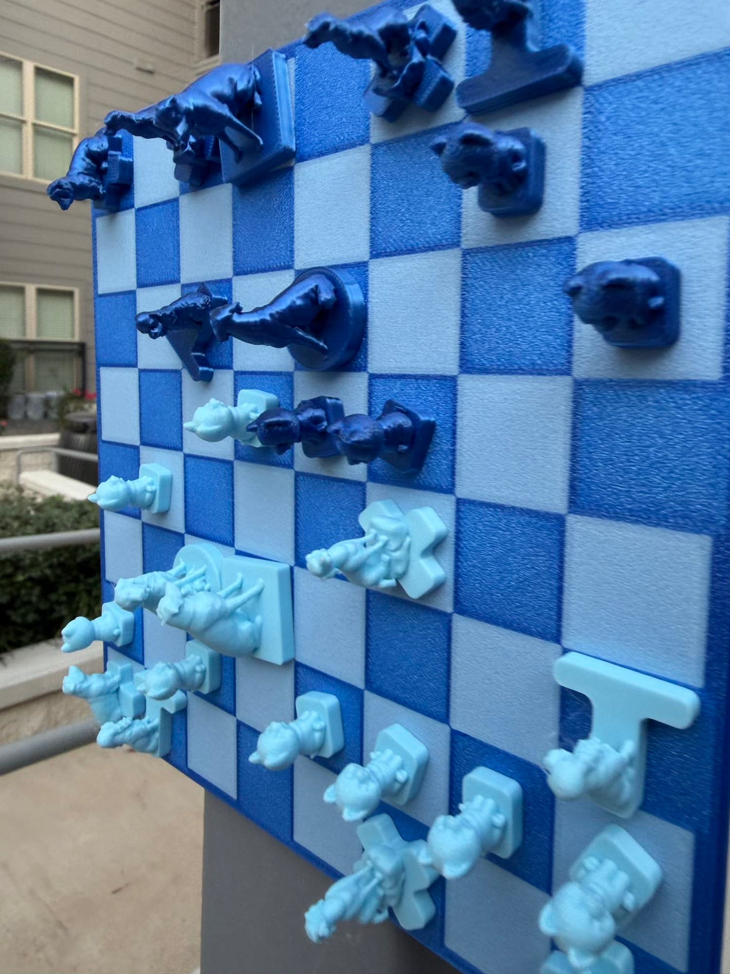 A closer angle shows dark and pale blue dog-shaped pieces gripping the vertical magnetic Fridge Chess board.