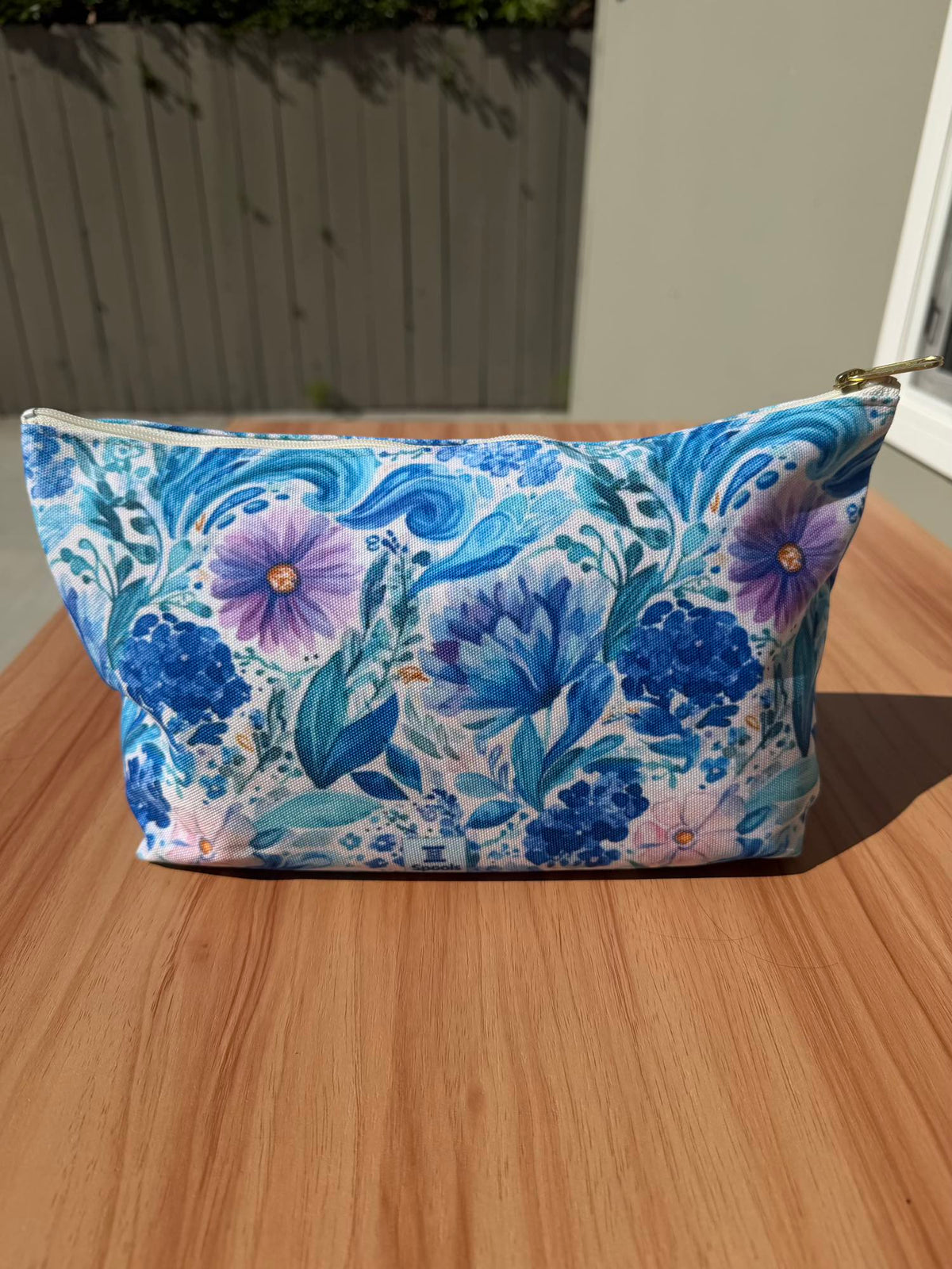 Reverse side of the blue and purple floral zippered pouch, plain florals with a small Spools tag near the base