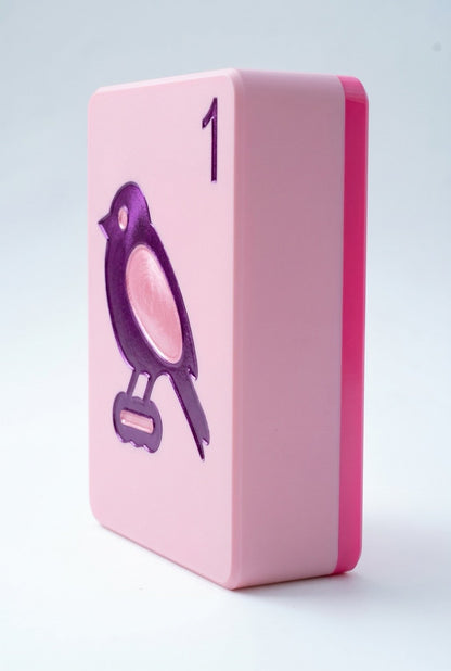 A pink rectangular block with rounded corners, featuring a purple bird illustration and the number 1 on the top face, photographed on a clean white background.