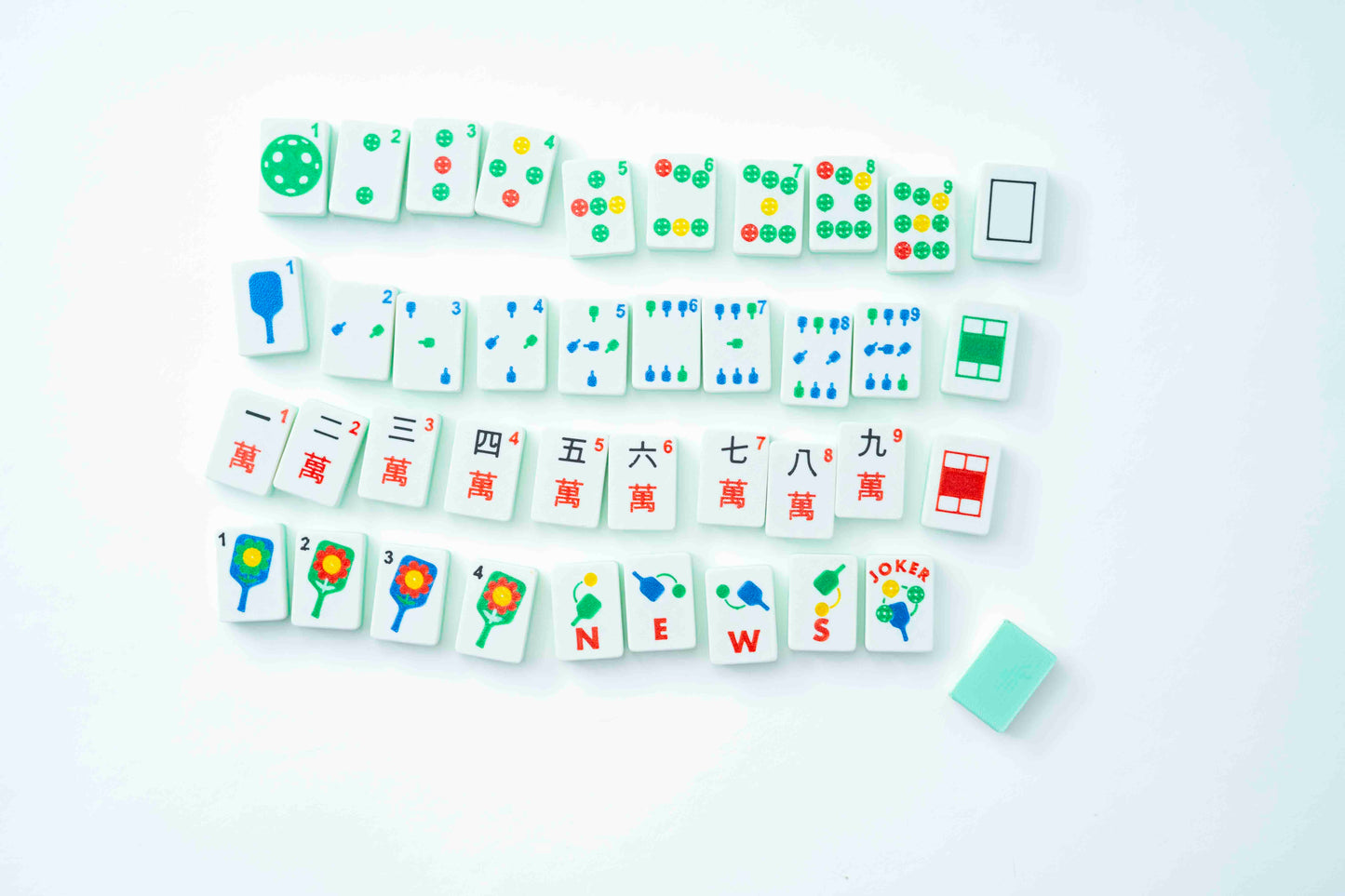 A set of white mahjong tiles arranged in rows on a clean white background, with a small light green tile placed beside them.