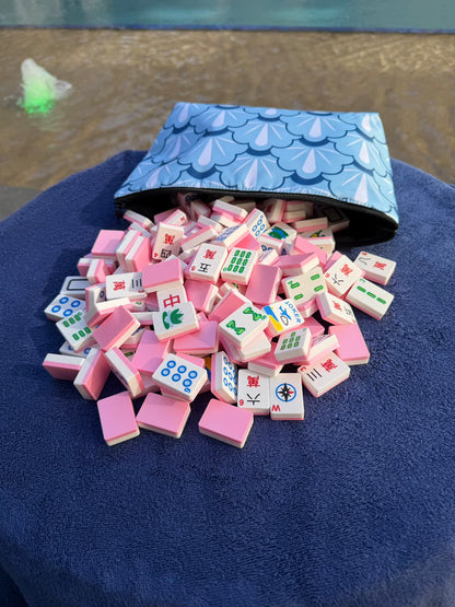 Spools Pink Compass mahjong tiles spilled from a carrying bag, showing lightweight pink tiles.
