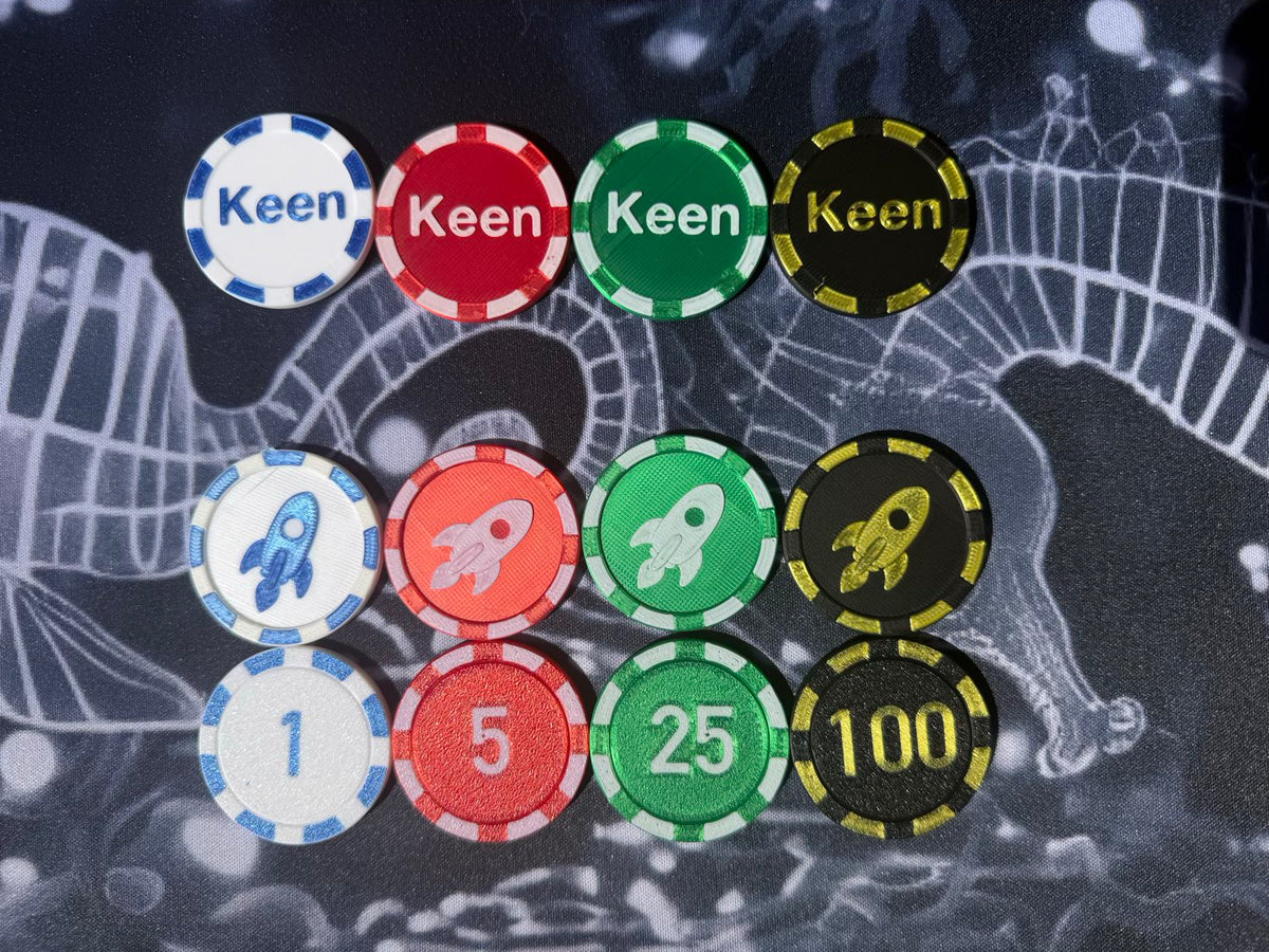 A set of poker-style chips arranged on a dark patterned surface. The chips include white, red, green, and black colors with numbers 1, 5, 25, 100 and the names Keen and Kaen.