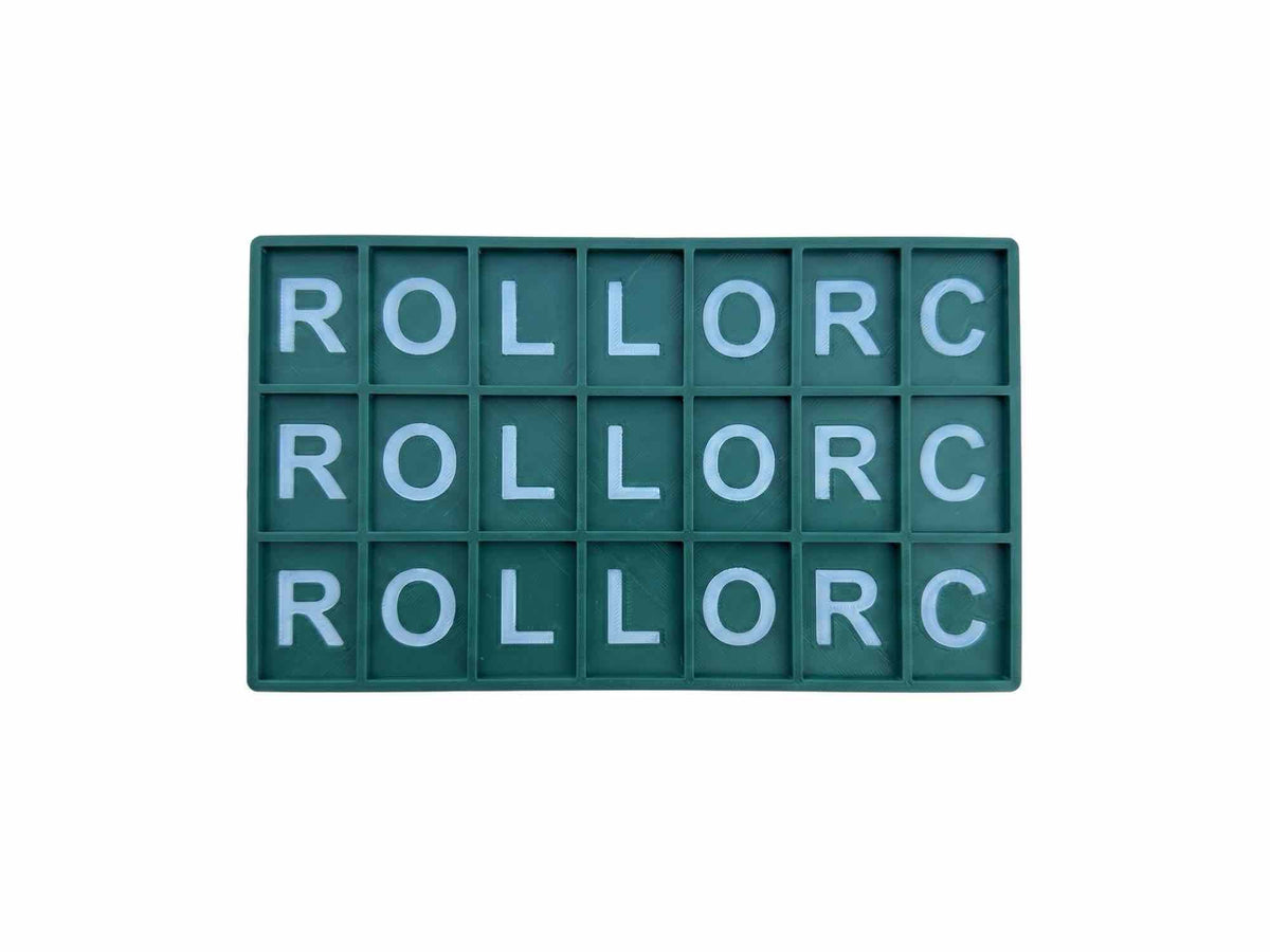 A rectangular green letter board with 18 compartments, each containing a light blue letter, arranged in three rows of six. The letters spell out 'ROLLORC' repeatedly.