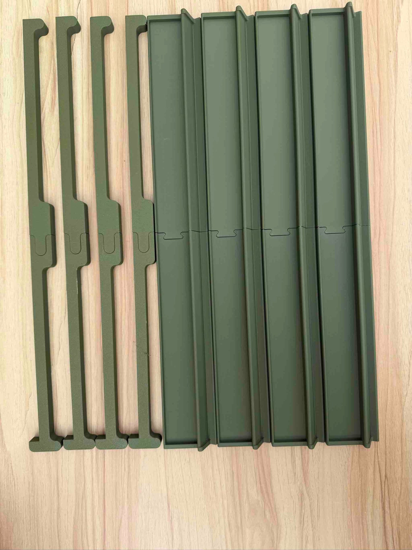 Set of green metal travel mahjong racks on a wooden surface