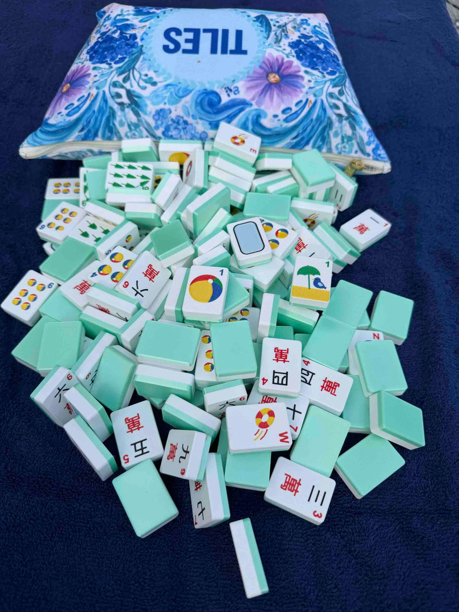 Mint green mahjong tiles with a floral-patterned box labeled 'TILES' on a dark blue background