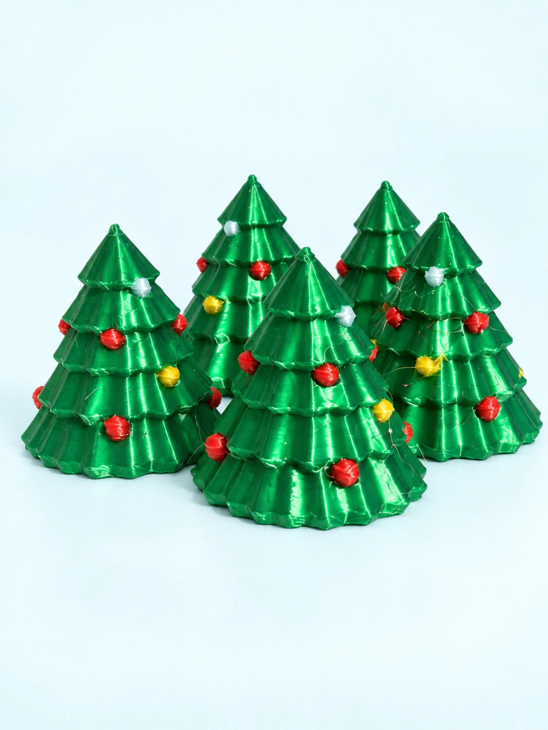 Five Christmas tree mahjong trinkets in green with red, gold, and white ornaments, 3D printed by Spools