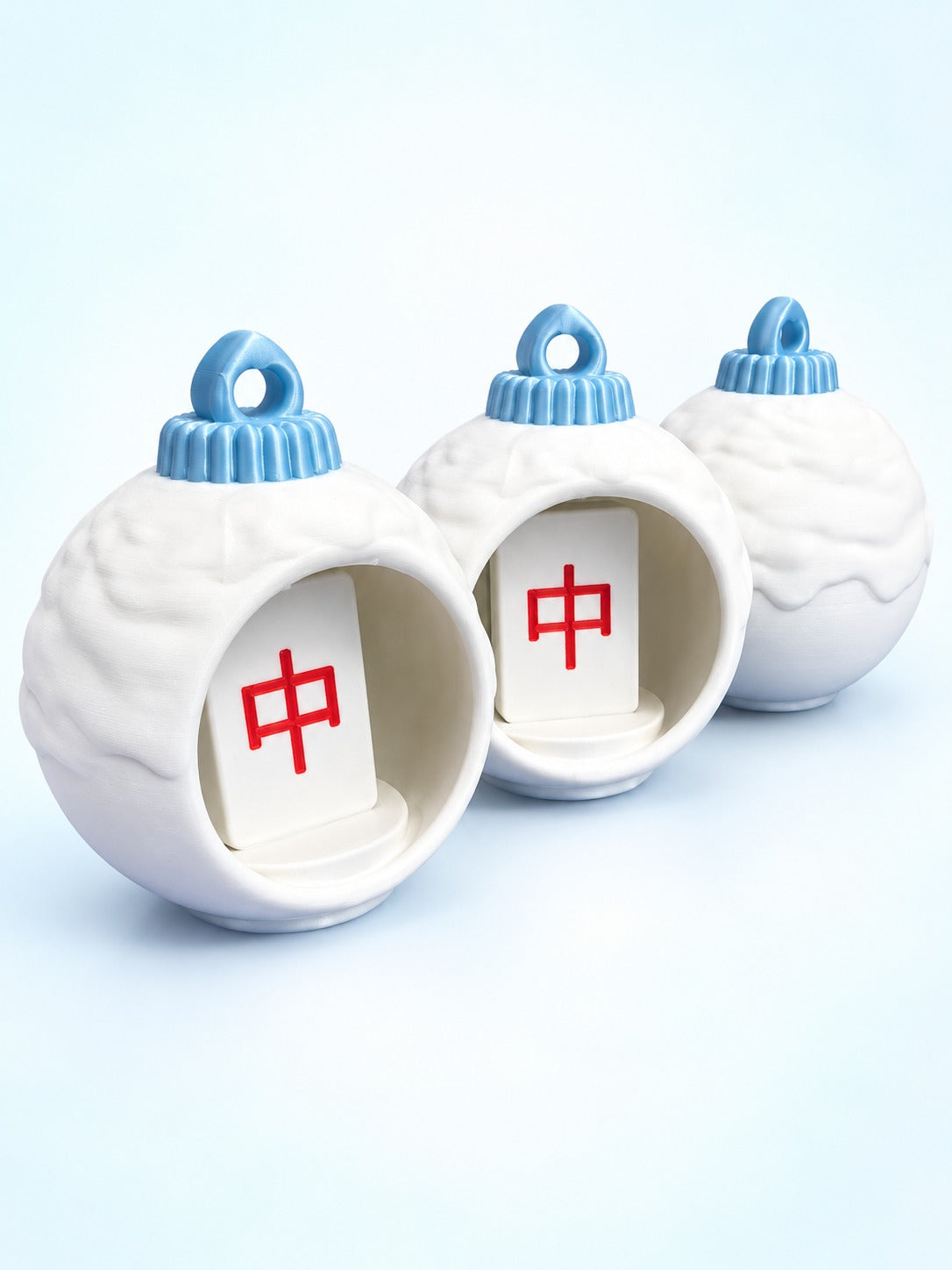 Side view of three mahjong bauble ornaments by Spools, two showing red dragon tiles inside
