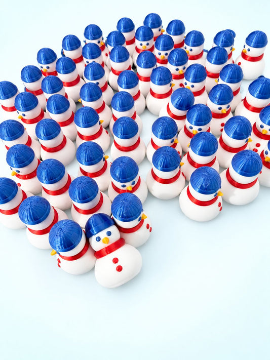Rows of snowman mahjong trinkets with blue hats, red scarves, and orange noses, 3D printed by Spools