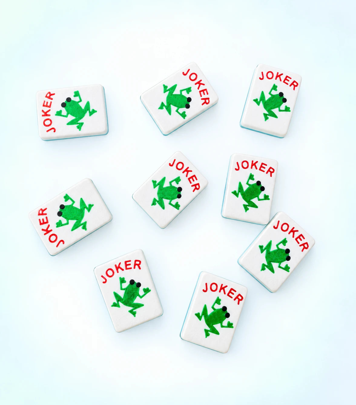Spools frog joker mahjong tiles, each with a green frog and red JOKER lettering, scattered across a light background