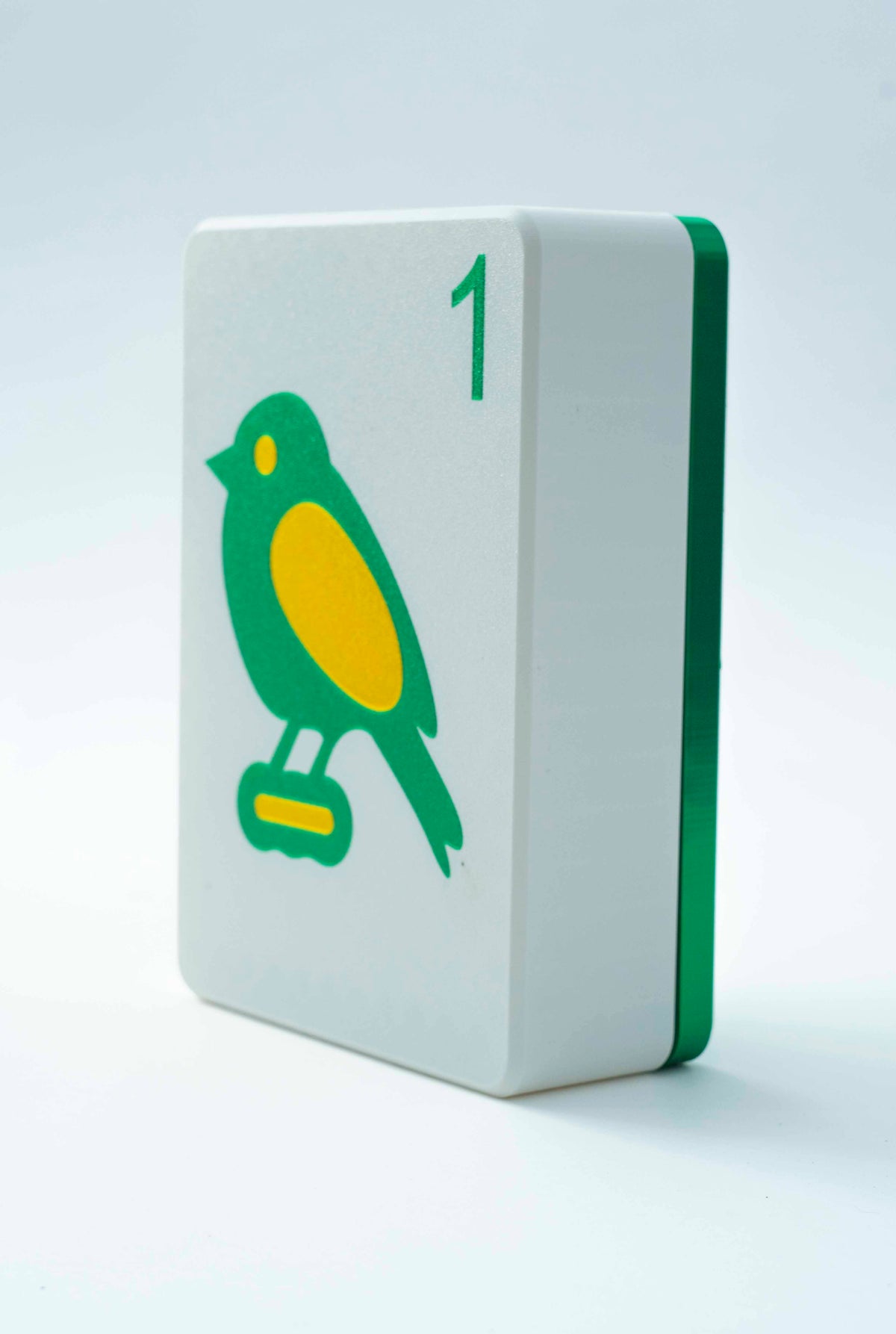 Spools mega mahjong tile display case with an emerald green back and white face showing the 1 bam bird, on a light gray background