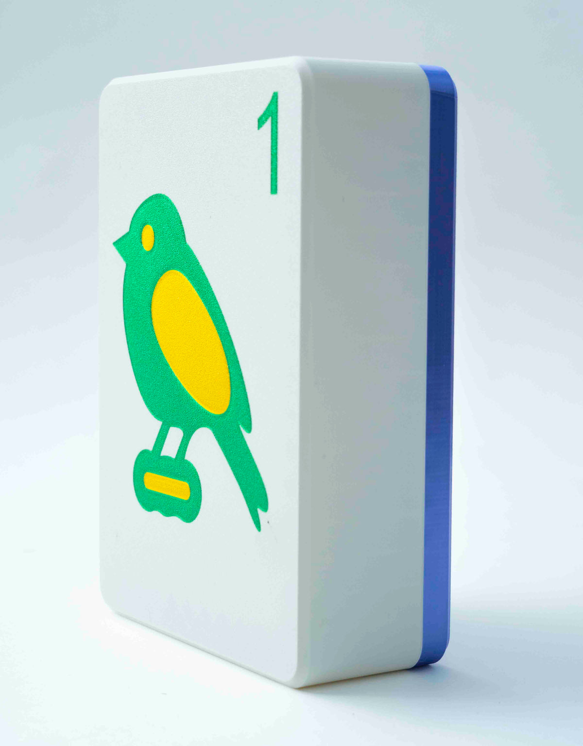 Spools mega mahjong tile display case with a purple back and white face showing the 1 bam bird, on a light gray background