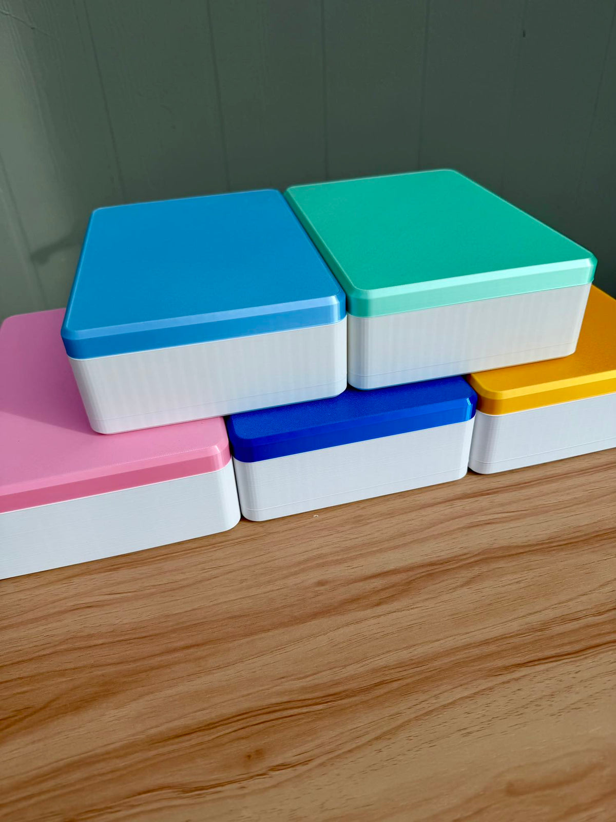 Five Spools mega mahjong tile display cases stacked, in blue, mint, pink, navy, and yellow