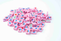 Pile of pink Spools nautical mahjong tiles with red and blue sailboat backs, fish, knots, buoys, and shells on a white background
