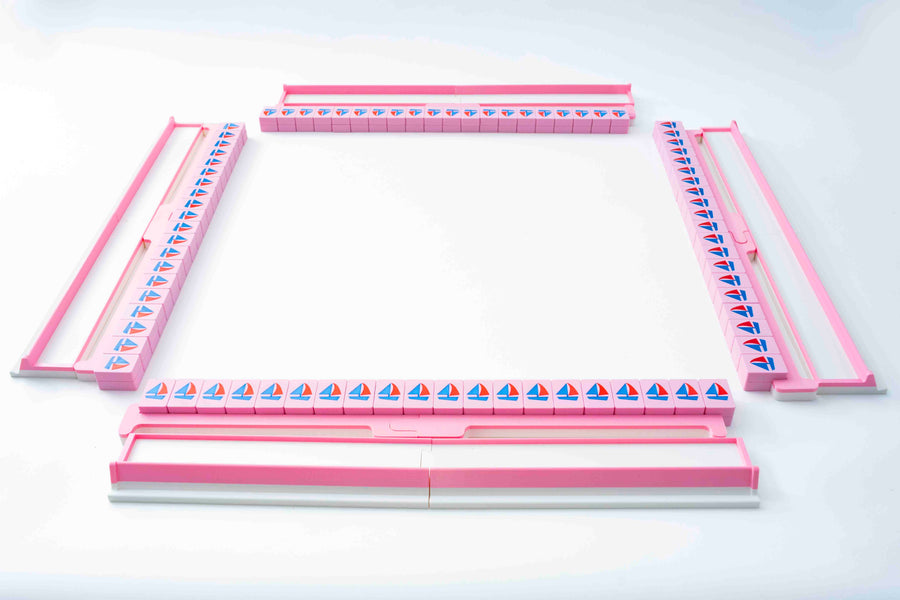 Four pink Spools travel racks holding walls of nautical mahjong tiles with sailboat backs, set up in a square for play