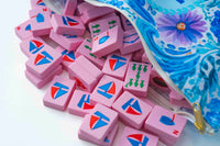 Pink Spools nautical mahjong tiles with sailboat backs, fish, and wind tiles spilling out of a blue floral tile pouch
