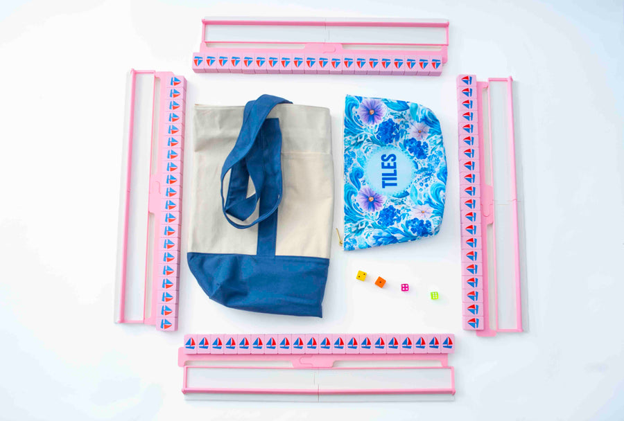 Pink Spools nautical mahjong travel bundle from above: four split racks with sailboat tile walls, canvas tote, floral tile pouch, and four dice
