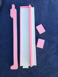 Overhead image of the pink Travel Mahjong rack pieces and tiles displayed on a navy towel.